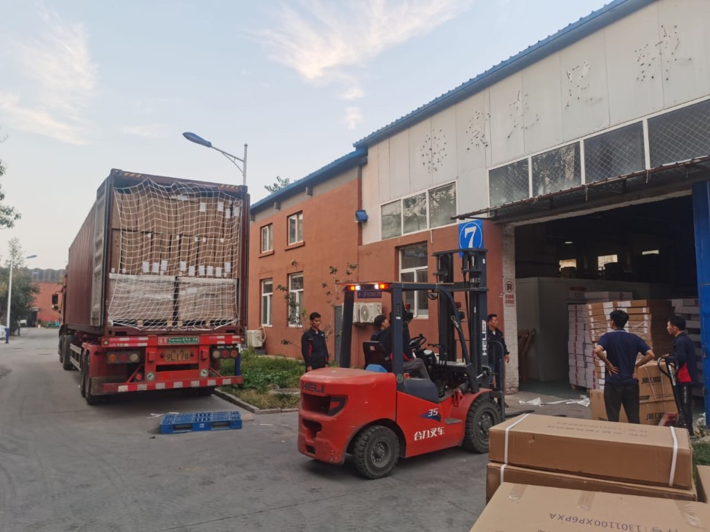 Operarios y montacargas descargando un contenedor de importación frente a la bodega